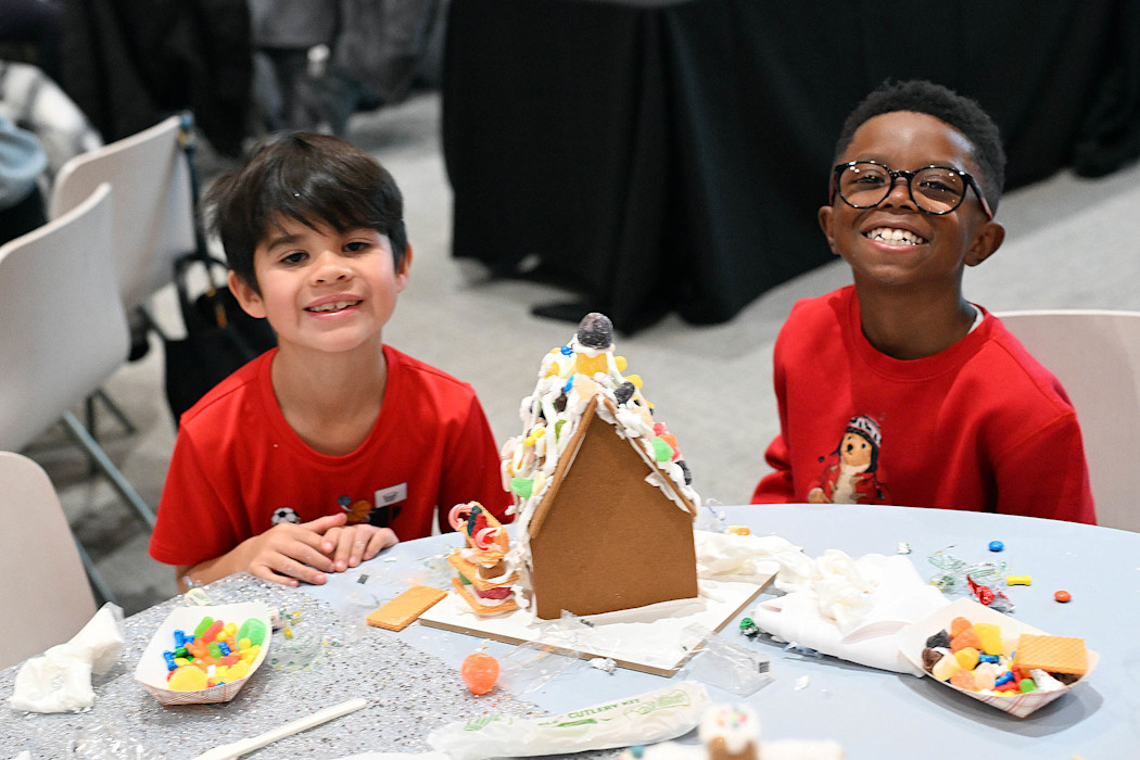 Two children build gingerbread houses. 