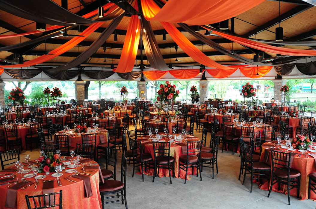 The pavilions room is decorated with orange tablecloths and roses. 