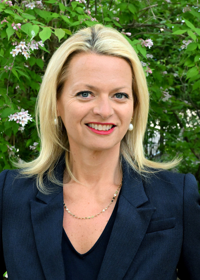 Andrea Rodgers smiles in front of a blooming tree.