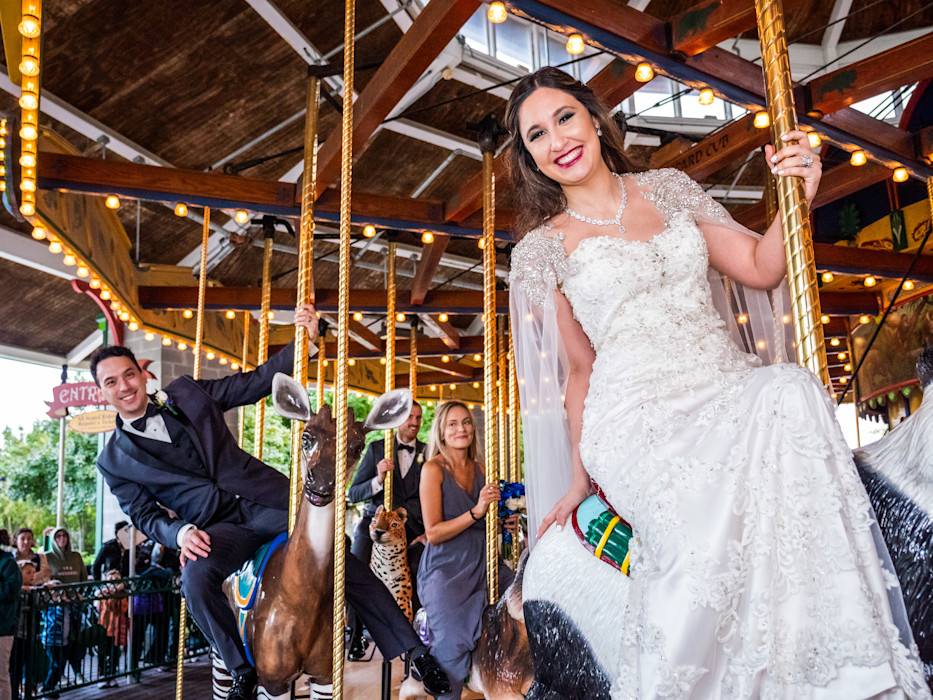 A bride and groom ride a carousel. 