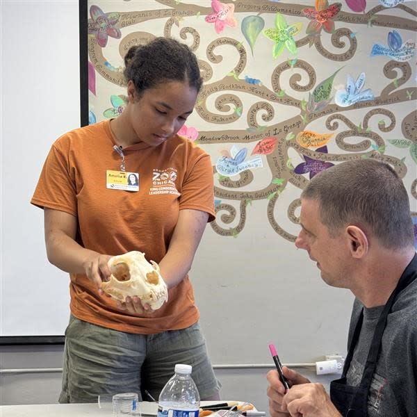 A high school student shows a guest a skull. 