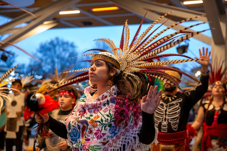 A Native American woman performs a dance. 