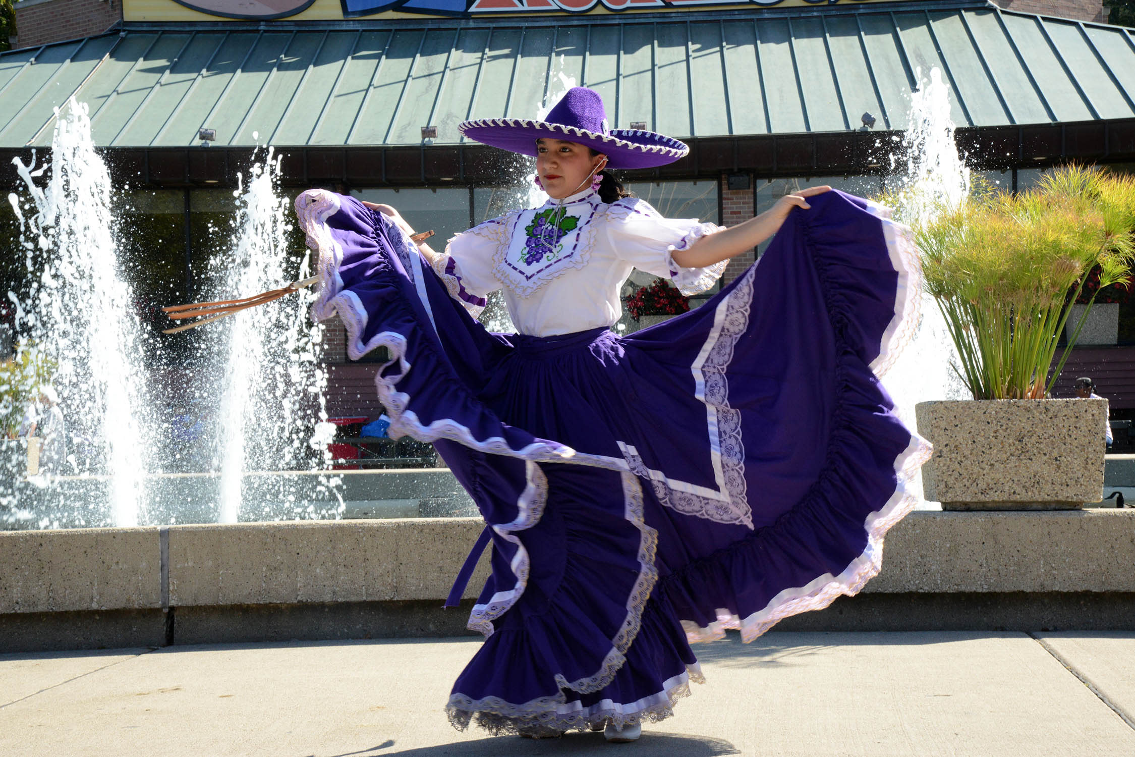 A woman dances and fans out her skirt in a traditional Hispanic outfit.