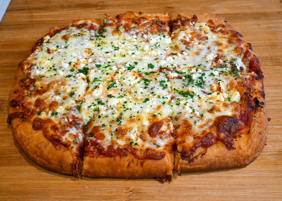 A cheese pizza on a wood table. 