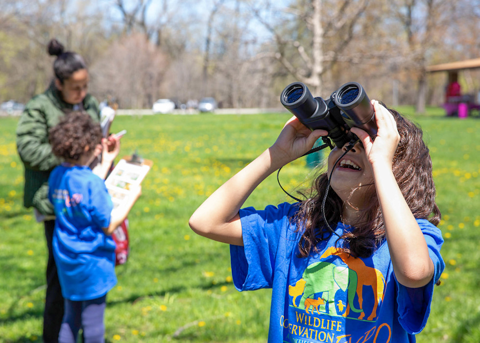 A child looks at the sky with a pair of binoculars. 