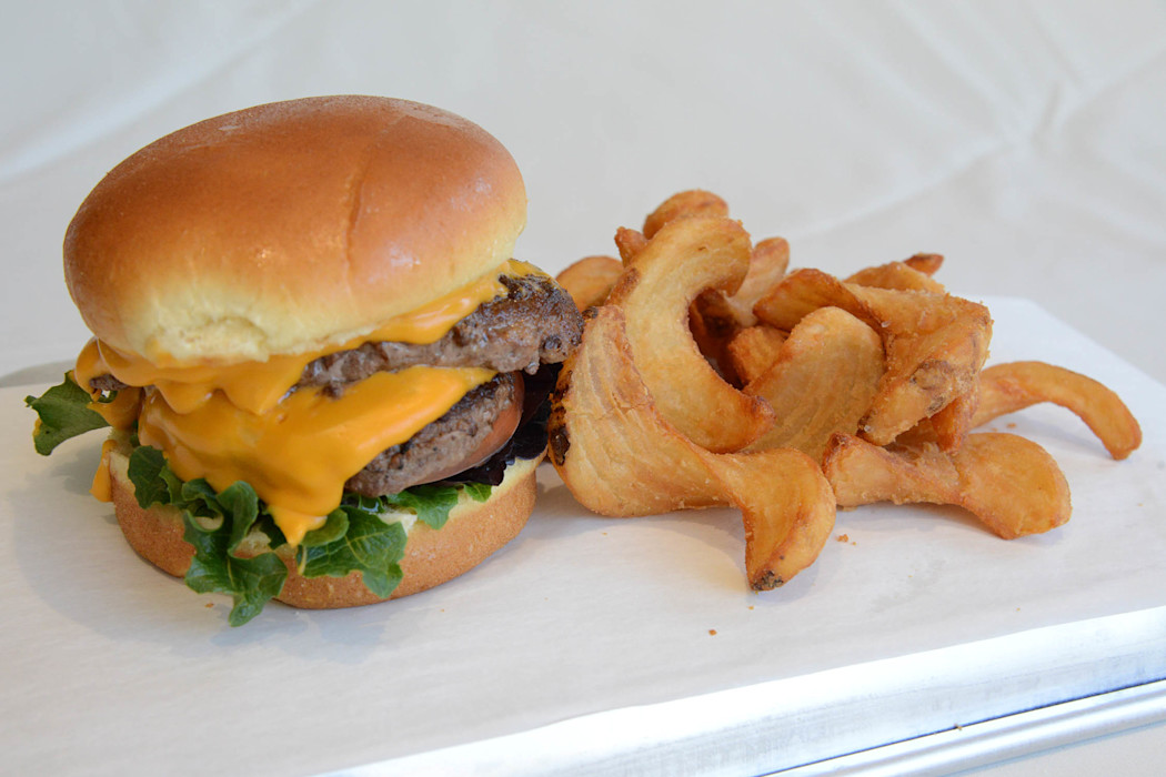 A cheeseburger sits on a plate with potato chips.