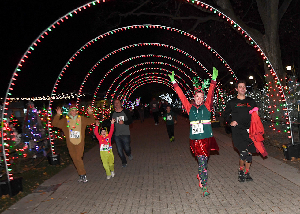 Guests dressed in festive costumes run through a lighted tunnel. 