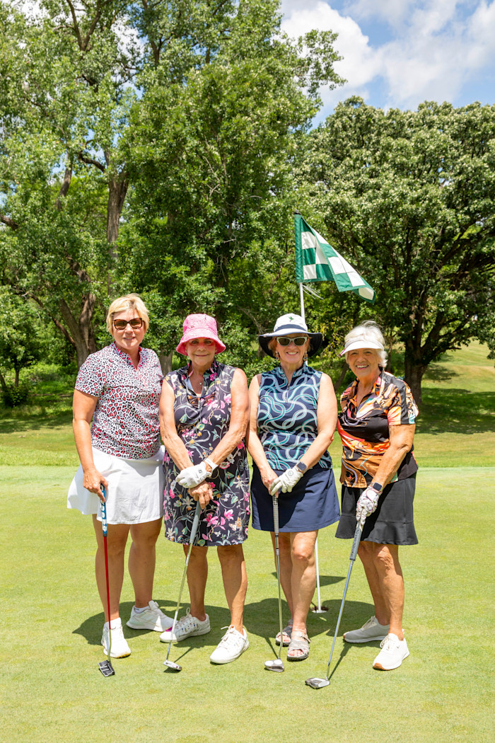 Four golfers stand on the course. 