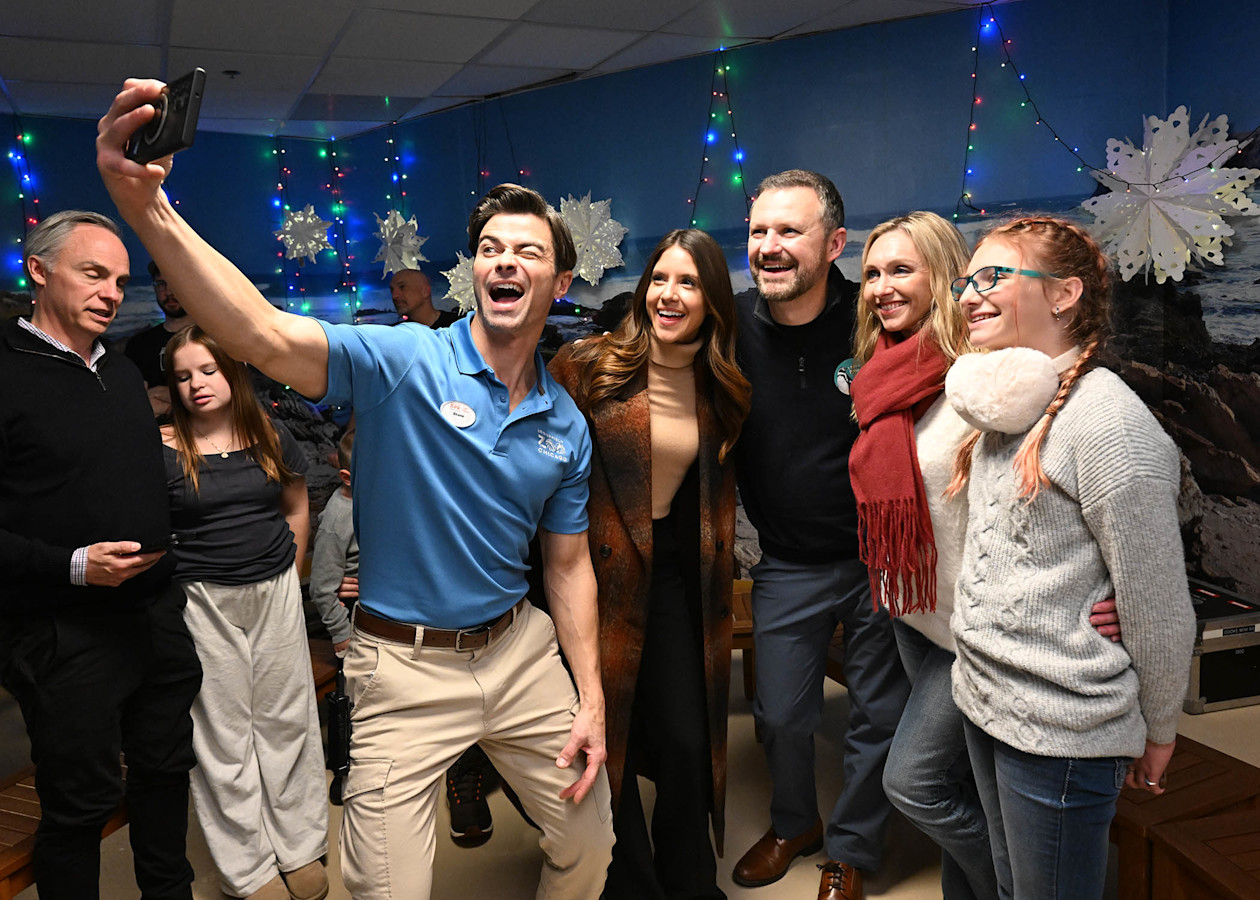An actor takes a selfie with a group. 
