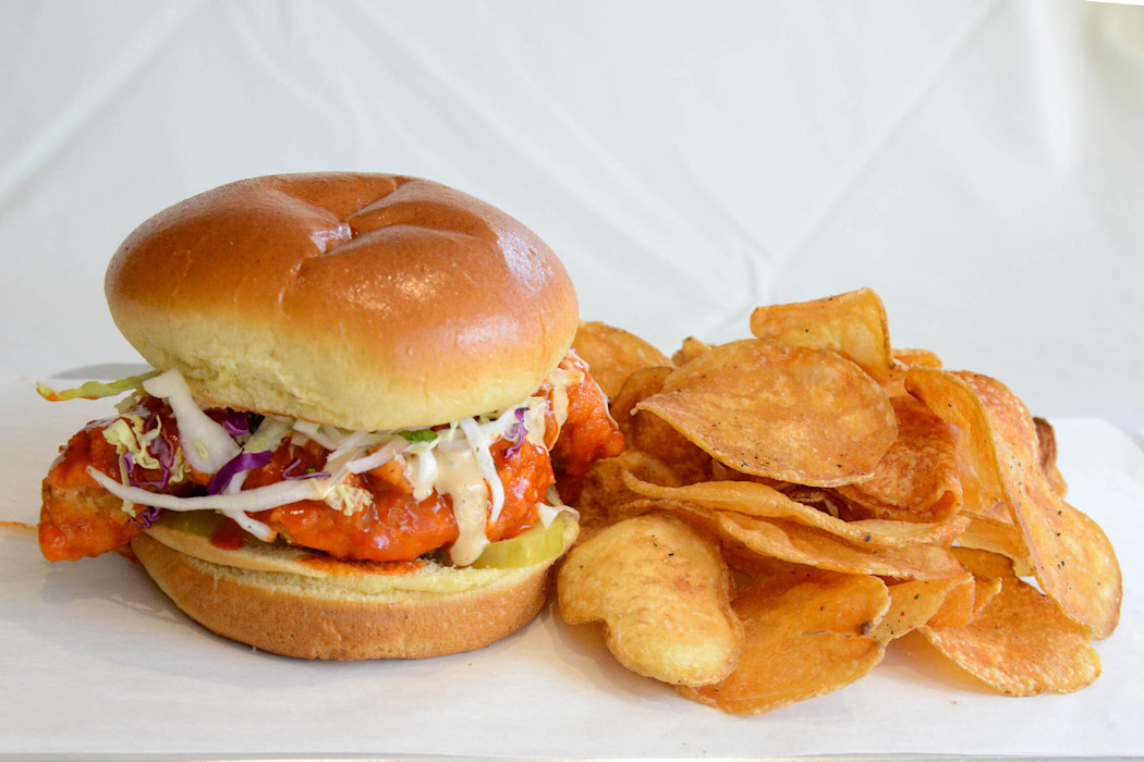A plate with a chicken sandwich and chips. 