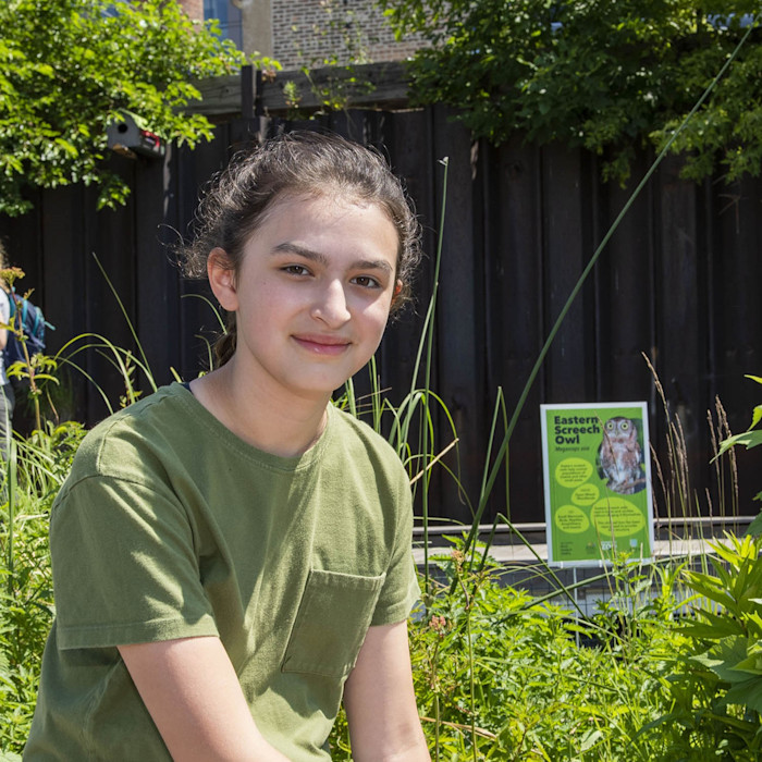 A middle-school aged student sits among tall grasses. 