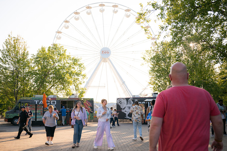 Guests explore Brookfield Zoo Chicago with 110-foot Ferris Wheel in the background.